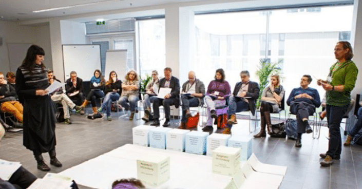 Menschen sitzen im Kreis bei einer Veranstaltung zur Veröffentlichung des Kompetenzrahmens von aufZAQ.