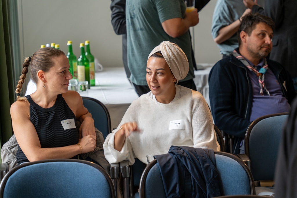 Zwei Frauen im Gespräch bei aufZAQ Impuls.Brunch, weitere Personen im Hintergrund.