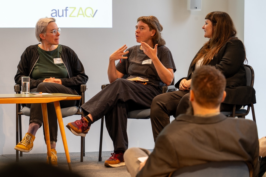 Drei Frauen sitzen auf Stühlen während eines aufZAQ Impuls.Brunchs und diskutieren. Publikum im Vordergrund.