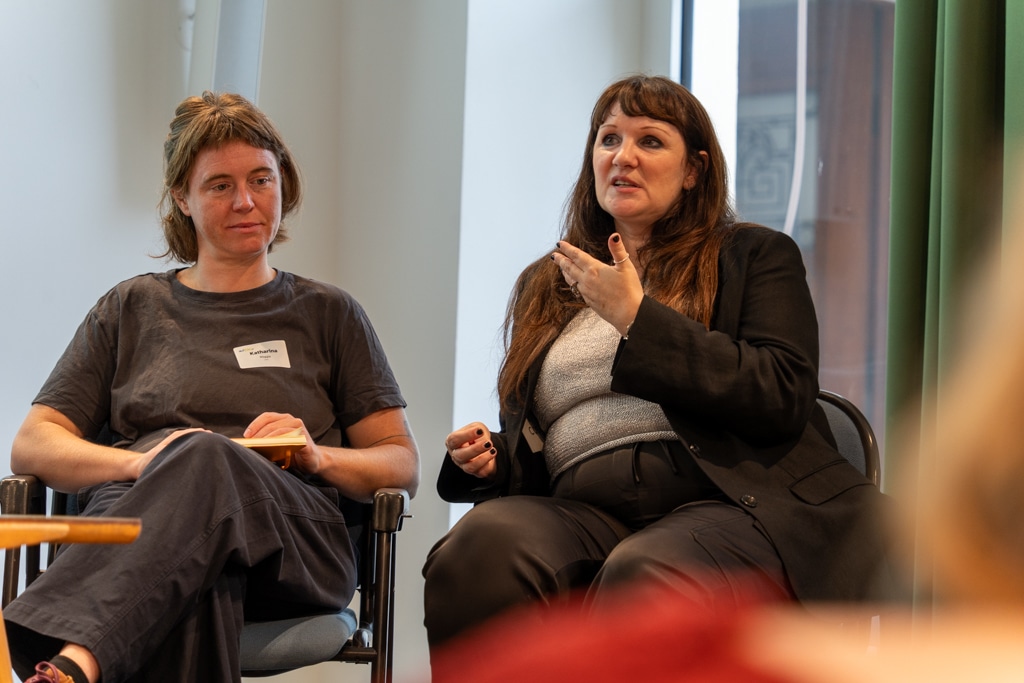 Zwei Frauen sitzen bei einem aufZAQ Impuls.Brunch und diskutieren. Eine Frau gestikuliert, die andere hört zu.