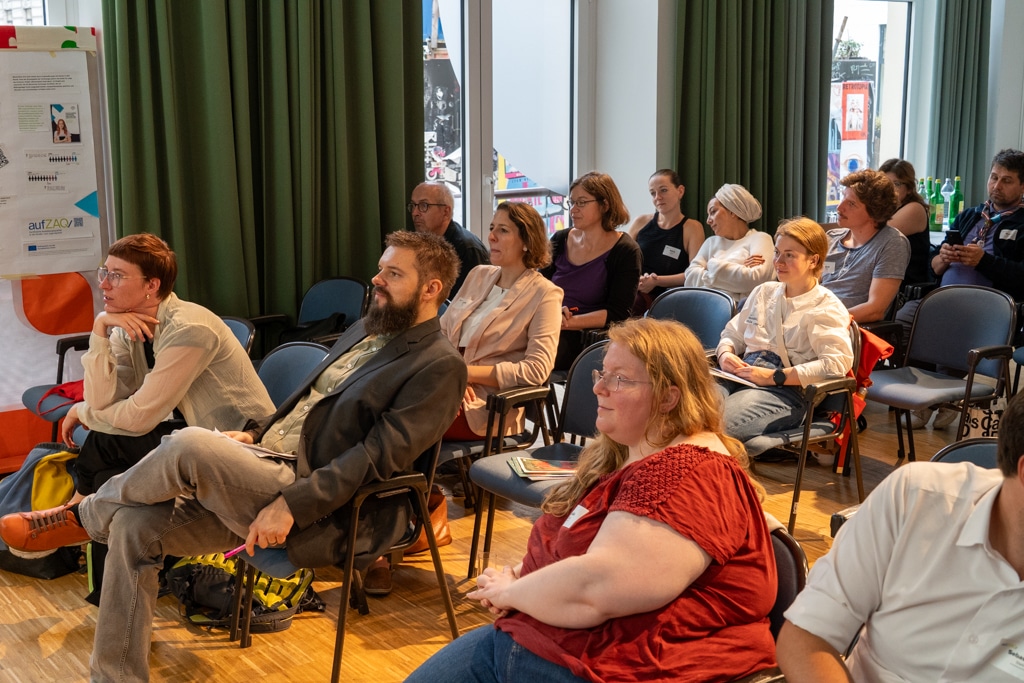 Zuhörer sitzen auf Stühlen bei einem aufZAQ Impuls.Brunch und verfolgen aufmerksam die Präsentation.