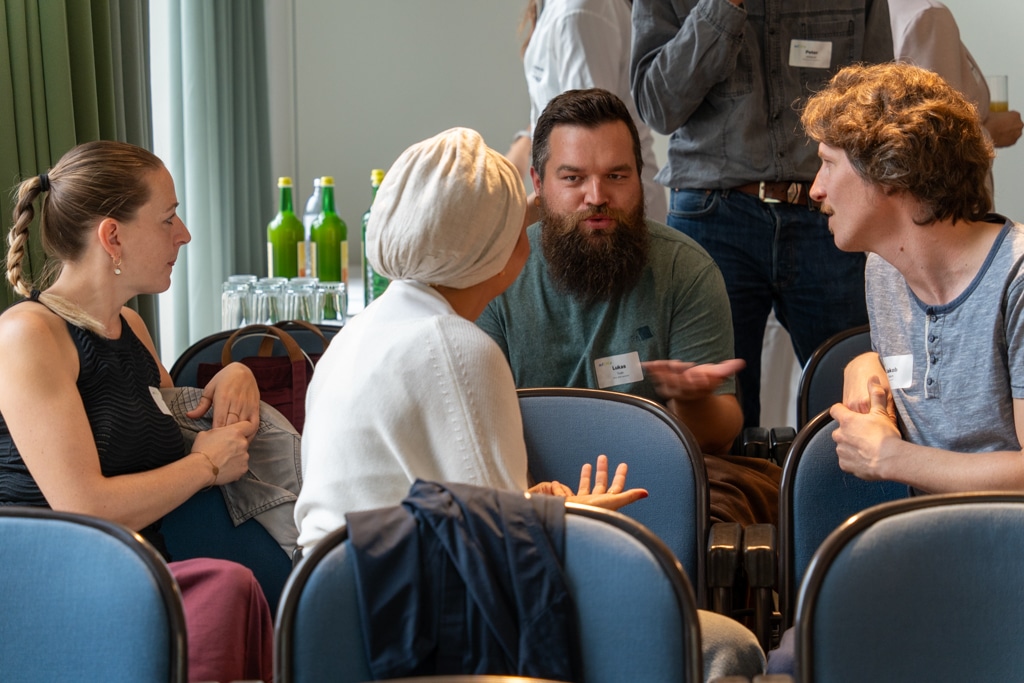 Menschen unterhalten sich angeregt bei einem aufZAQ Impuls.Brunch. Fokus auf Gesprächsgruppen.