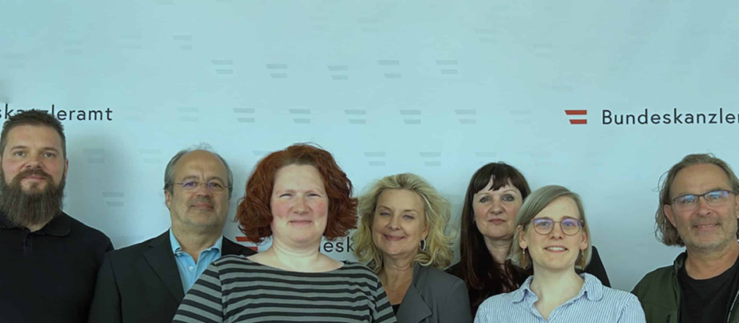 Gruppenfoto des neuen aufZAQ-Beirats vor dem Logo des Bundeskanzleramts.